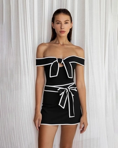 Close-up of contrast bow detail on a black off-shoulder one-piece swimsuit