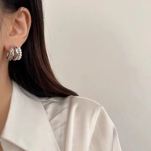 Close-up of triple-layered hoop earrings with pearls and twisted silver texture