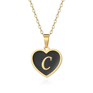 Detail shot of golden heart pendant featuring a black enamel center with a gold letter C