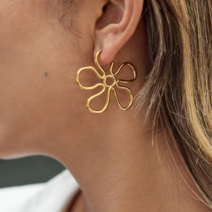 Close-up of model wearing gold minimalist hollow flower earrings with artistic metal lines