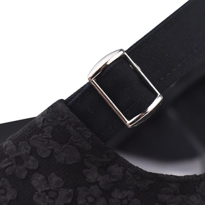 Dettaglio del cappellino in pizzo nero con trama jacquard floreale e fibbia in metallo