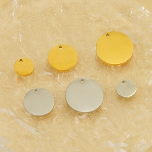Minimalist 18k gold and silver stainless steel round pendant tags on a glass tray