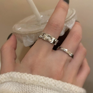 Close-up of stacked silver irregular textured rings and twisted rope band on hand