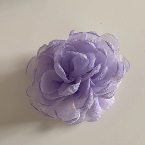 Close-up of a light purple organza rose hair claw with layered shimmering fabric petals