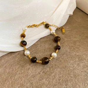 Tiger eye and pearl beaded bracelet with gold-plated accents on soft fabric background