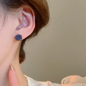 Gros plan de boucles d'oreilles roses en résine violette portée avec détails 3D