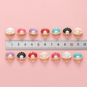 Detail showing colorful shell charms with pearls and size measurement on pink background