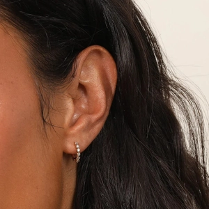 Close-up of rose gold hoop earrings with pavé zircons worn on the earlobe