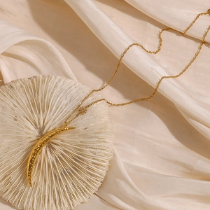 Detail of 18K gold crescent moon and star pendant necklace on silk fabric background