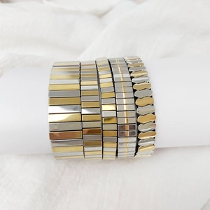 Detail of five gold and silver bicolor stretch bracelets on a white display stand