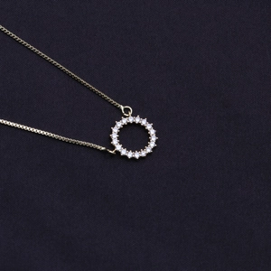 Nahaufnahme der goldenen Box-Kette mit rundem Zirkonia-Anhänger auf schwarzem Stoff