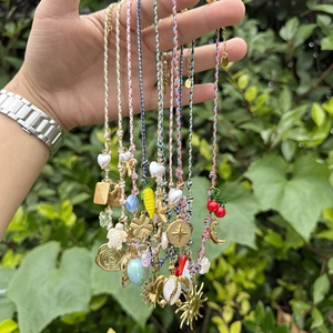 Détail de colliers tressés colorés avec des breloques étoile de mer et tortue sur une main