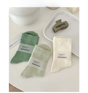 Detailansicht von Baumwoll-Stulpen-Socken in Grün und Creme mit Papierband-Verpackung