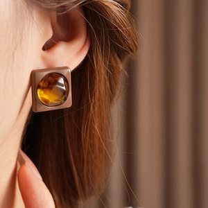 Close-up of amber resin square earring showing geometric design and glossy texture