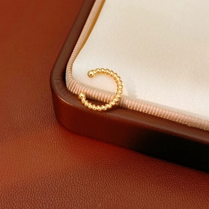 Close-up of twisted 18k gold plated ear cuff with polished texture on silk background