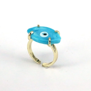 Close-up of golden evil eye ring with blue resin stone and adjustable open band