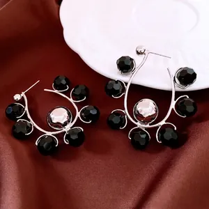Chic silver needle earrings with black faceted glass beads on a satin background