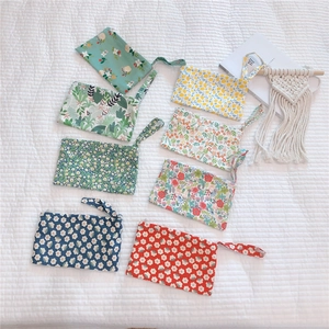Flat lay of small cotton floral pouch bags with wristlets in assorted patterns