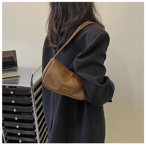 Detailed side view of a brown vintage leather underarm bag with gold fashion lettering