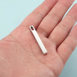 Minimalist silver stainless steel bar pendant held in hand showing size and polished finish