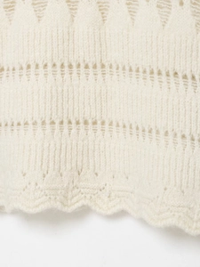 Detailed view of cream pointelle knit fabric with delicate scalloped hemline texture