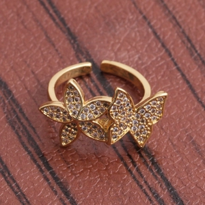 Adjustable golden butterfly ring with sparkling cubic zirconia on brown leather surface