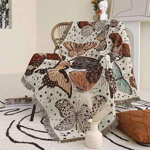 Detail of bohemian woven blanket with butterfly patterns and tassel edges on a chair
