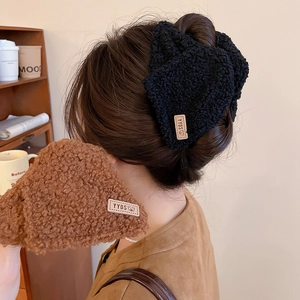 Detailopname van pluche haarscrunchies in zwart en bruin met geweven beertjeslabels