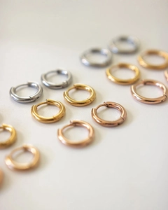 Detailed view of polished silver, gold, and rose gold huggie hoop earrings with hinges