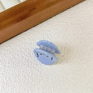 Close-up of a mini light blue cloud hair claw clip with cute facial expression detail