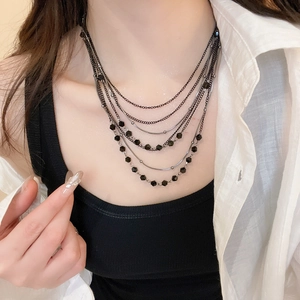 Detail of multi-layer crystal beaded necklace featuring black chains and elegant textures