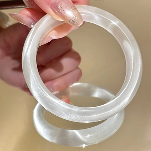 Close-up of translucent white cat eye stone bangle with silk luster on hand