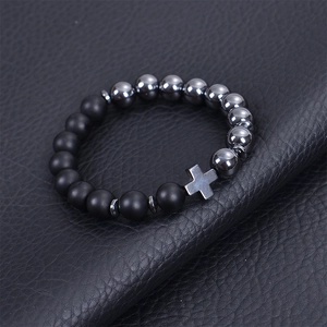 Men's natural matte black stone beaded cross bracelet with elastic cord on leather background