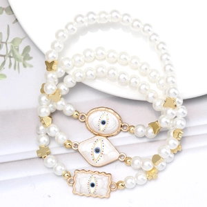 Three-piece set of faux pearl bracelets with golden evil eye charms and clover details