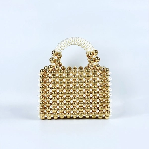 Detail of handcrafted evening bag with golden beads and white pearls woven texture