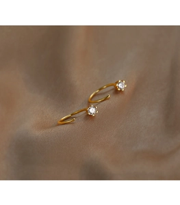 Macro shot of gold-plated C-shaped earrings featuring a six-prong set clear zircon detail