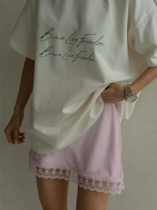 Detailed view of pink satin midi skirt with delicate lace trim and white graphic tee