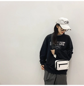 Detail of white PU camera-style crossbody bag with black contrast zippers and wide strap