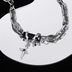 Detail view of double-layer silver chain necklace with black gem and cross pendant