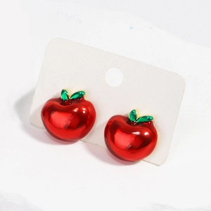 Gros plan de boucles d'oreilles pommes rouges avec feuilles vertes sur carte blanche