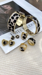 Close-up of leopard print jewelry set featuring gold rings and earrings on white fabric