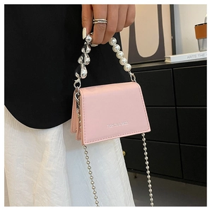 Detailed close-up of pink mini crossbody bag with pearl handle and silver chain strap