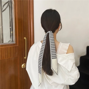 Dettaglio di un nastro per capelli con motivo pied de poule bianco e nero sui capelli