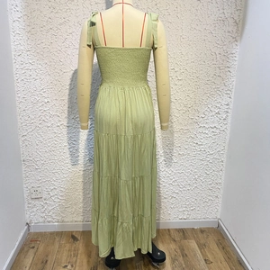 Detail of smocked elastic back and tiered green summer dress on a mannequin