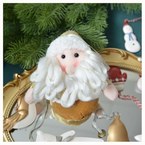Detail of plush Santa ornament with white curly beard on vintage mirror and pine branches