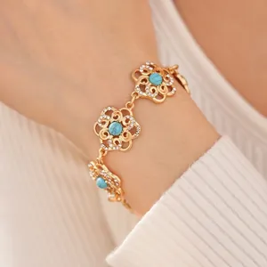 Vintage gold hollow flower bracelet with turquoise stone and crystal accents on white knit