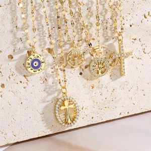 Detail of gold cross and tree of life pendants with zircon stones on stone background
