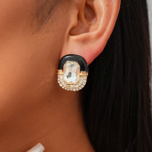 Detail of luxury gold stud earrings featuring black enamel and sparkling rhinestones