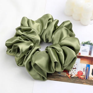 Detail of moss green oversized satin scrunchie with elegant silk texture and soft folds