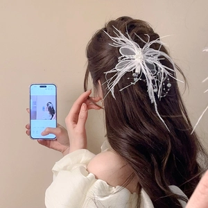 Détail de la barrette à cheveux en plumes blanches et perles sur une coiffure